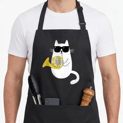 Horn cute cat apron - White cartoon cat wearing black sunglasses playing a yellow french horn — shown on a black cotton canvas apron against a white background