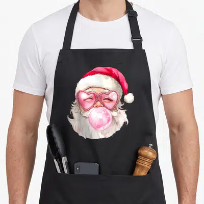 Santa pink christmas apron - Watercolor Santa head with pink heart sunglasses and bubblegum bubble in red and white — shown on a black cotton canvas apron against a white background