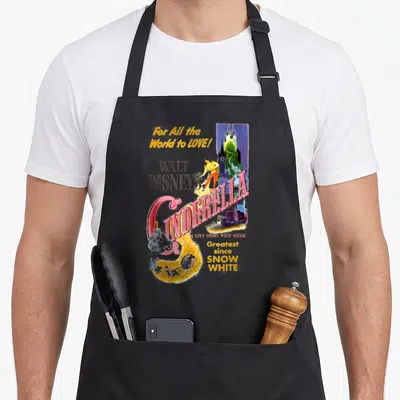 Movie cinderella apron - Retro Cinderella movie poster print with Prince, carriage, and castle in pink, blue, and yellow — shown on a black cotton canvas apron against a white background