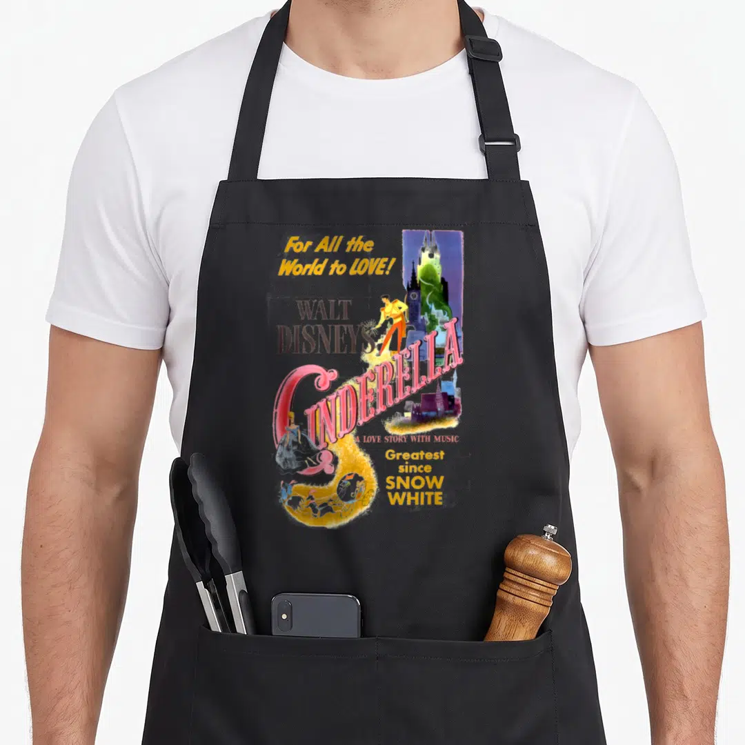 Movie cinderella apron - Retro Cinderella movie poster print with Prince, carriage, and castle in pink, blue, and yellow — shown on a black cotton canvas apron against a white background