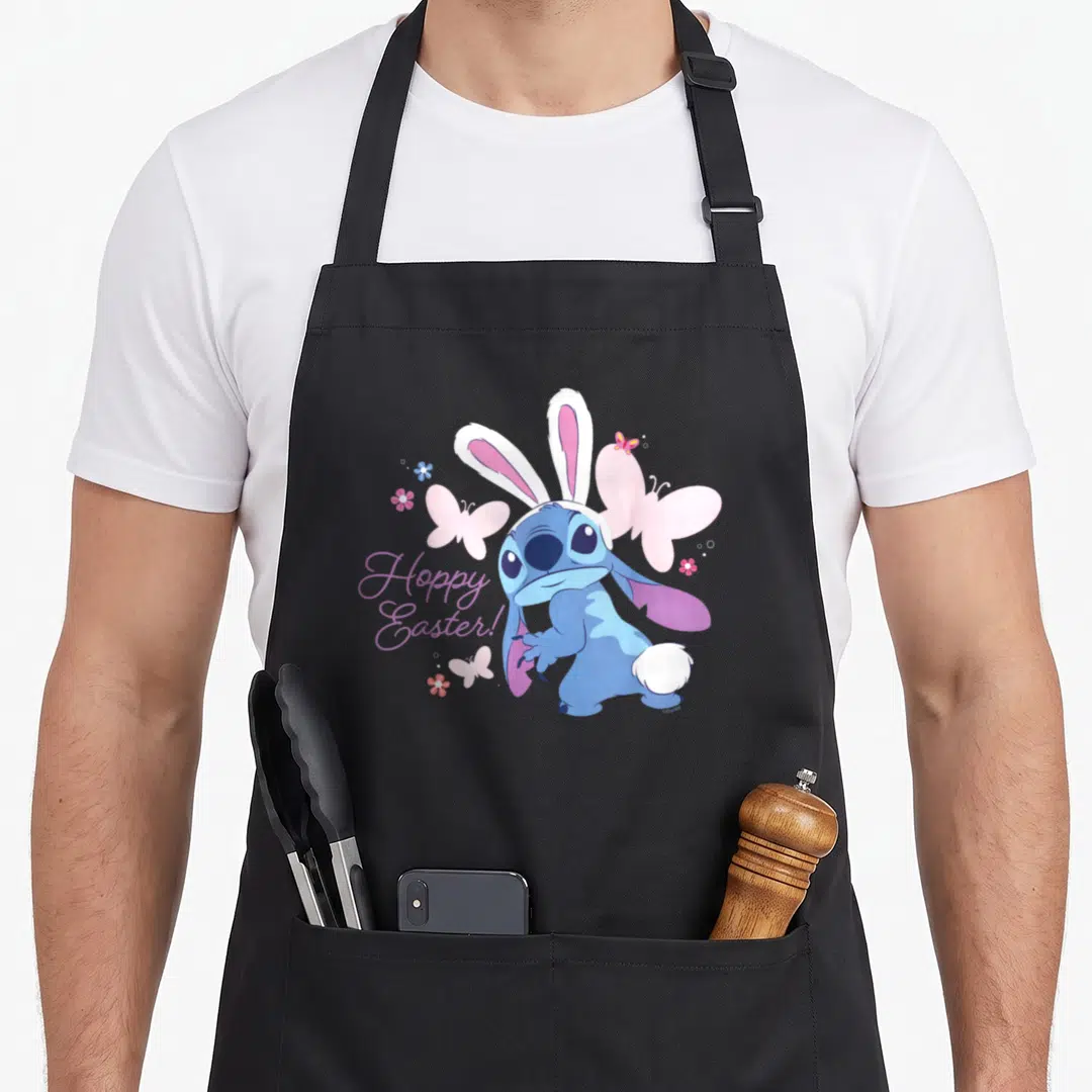 Hoppy stitch apron - Blue Stitch wearing bunny ears with pink butterflies and purple Hoppy Easter text — shown on a black cotton canvas apron against a white background