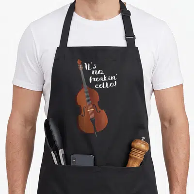 Double joke apron - Brown cartoon double bass next to white stacked text reading It's no freakin' cello! — shown on a black cotton canvas apron against a white background