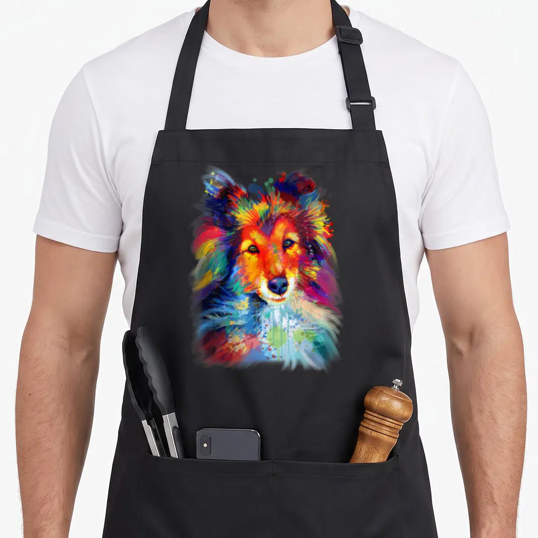 Shetland sheltie apron - Multicolored watercolor painting of a Shetland Sheepdog head in blue red yellow orange purple — shown on a black cotton canvas apron against a white background