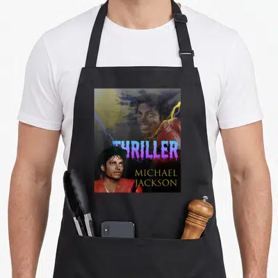 Thriller michaels apron - Two Michael Jackson portraits with yellow eyes, red jacket, blue lightning, purple moon — shown on a black cotton canvas apron against a white background