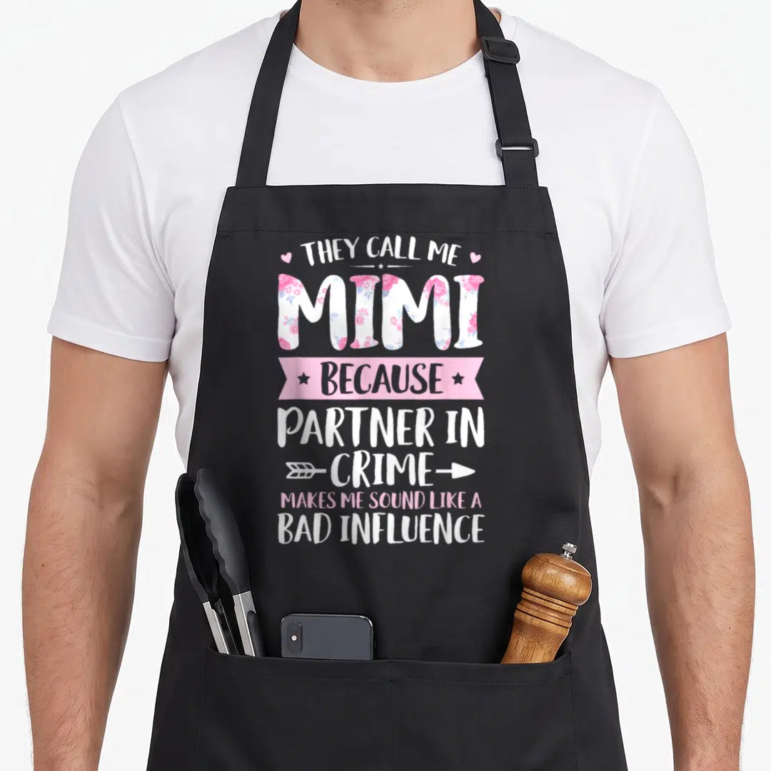They mother's day aprons - Mimi filled with flowers and partner in crime text with arrow — shown on a black cotton canvas apron against a white background