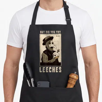 Leech doctor apron - Plague doctor holding skull with text BUT DID YOU TRY LEECHES beige black grey — shown on a black cotton canvas apron against a white background
