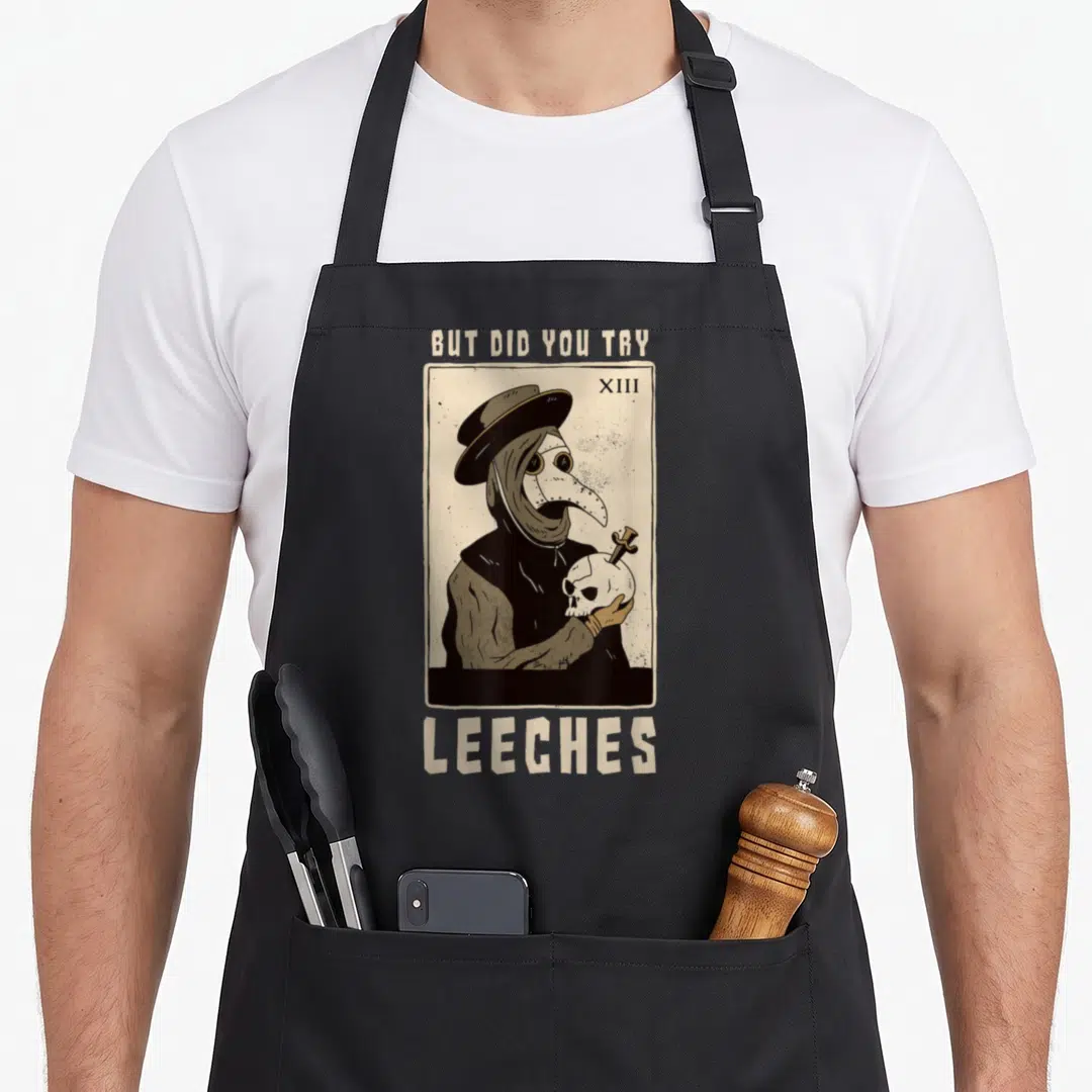 Leech doctor apron - Plague doctor holding skull with text BUT DID YOU TRY LEECHES beige black grey — shown on a black cotton canvas apron against a white background
