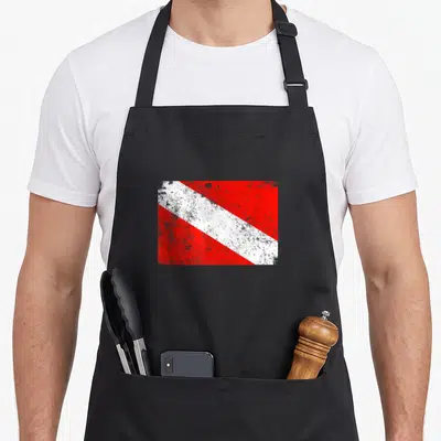 Worn diving apron - Distressed red and white diagonal stripe diving flag graphic — shown on a black cotton canvas apron against a white background