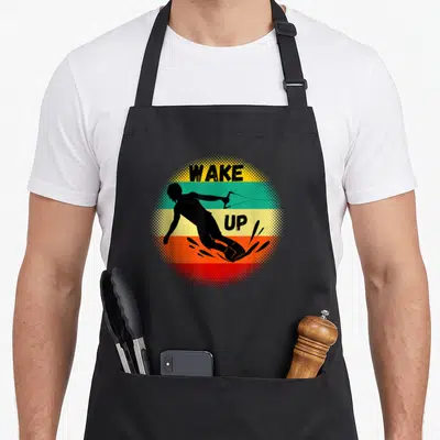 Surfing wakeboarding apron - WAKE UP text over wakeboarder silhouette with yellow green orange and red stripes — shown on a black cotton canvas apron against a white background