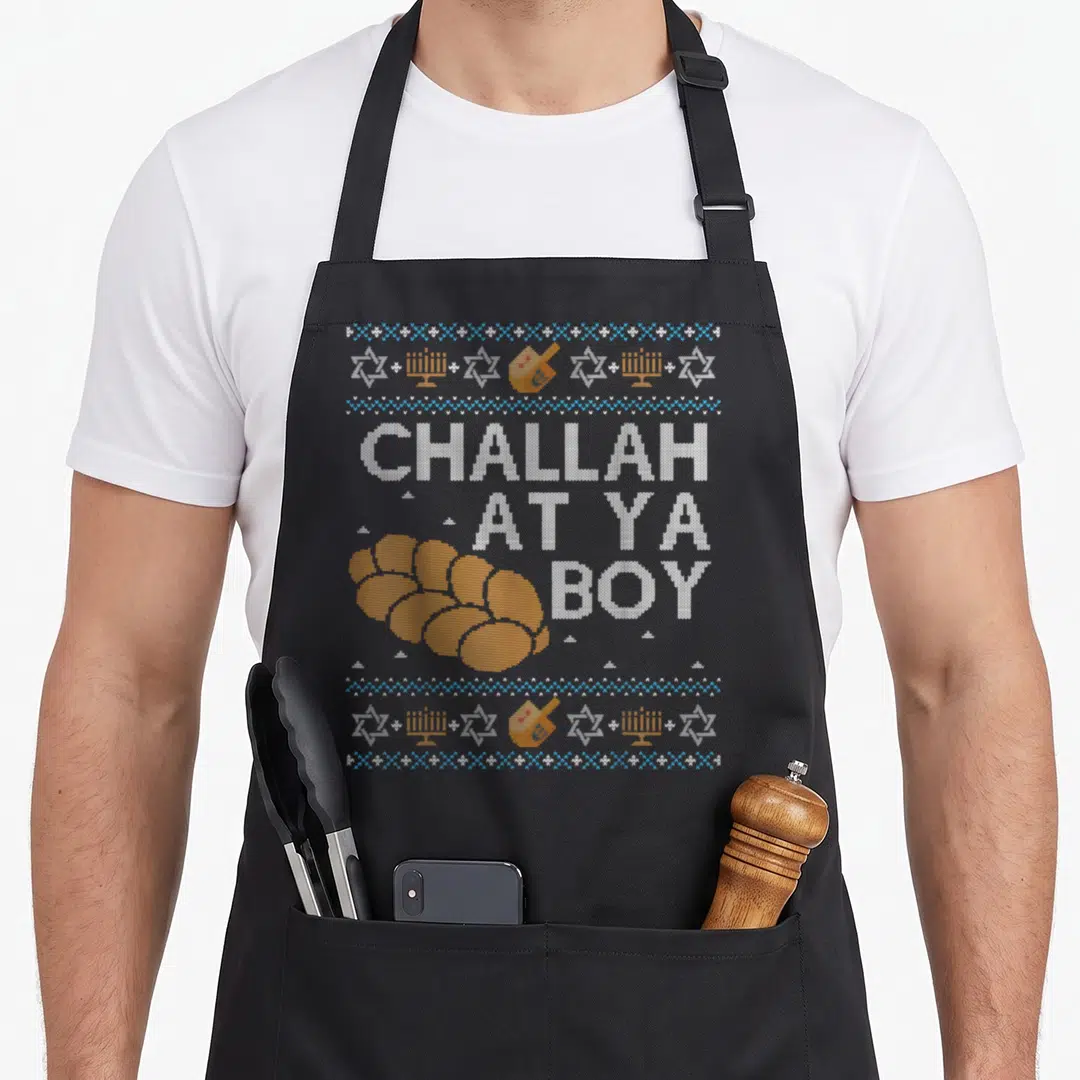Ugly hanukkah apron - Orange challah bread next to white text CHALLAH AT YA BOY with blue and white borders containing — shown on a black cotton canvas apron against a white background