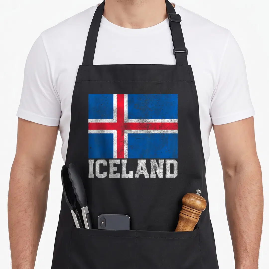 Iceland country apron - Distressed Iceland flag graphic above white ICELAND text on black fabric — shown on a black cotton canvas apron against a white background