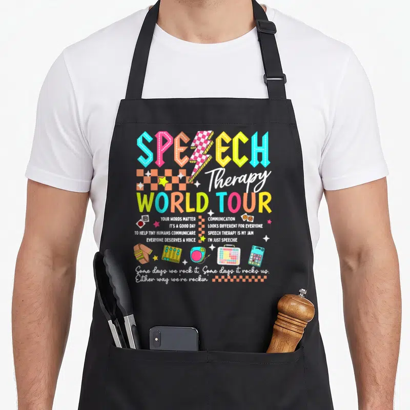 Tour my therapy apron - Retro style speech therapy design with colorful text, mixer icon, and AAC devices — shown on a black cotton canvas apron against a white background