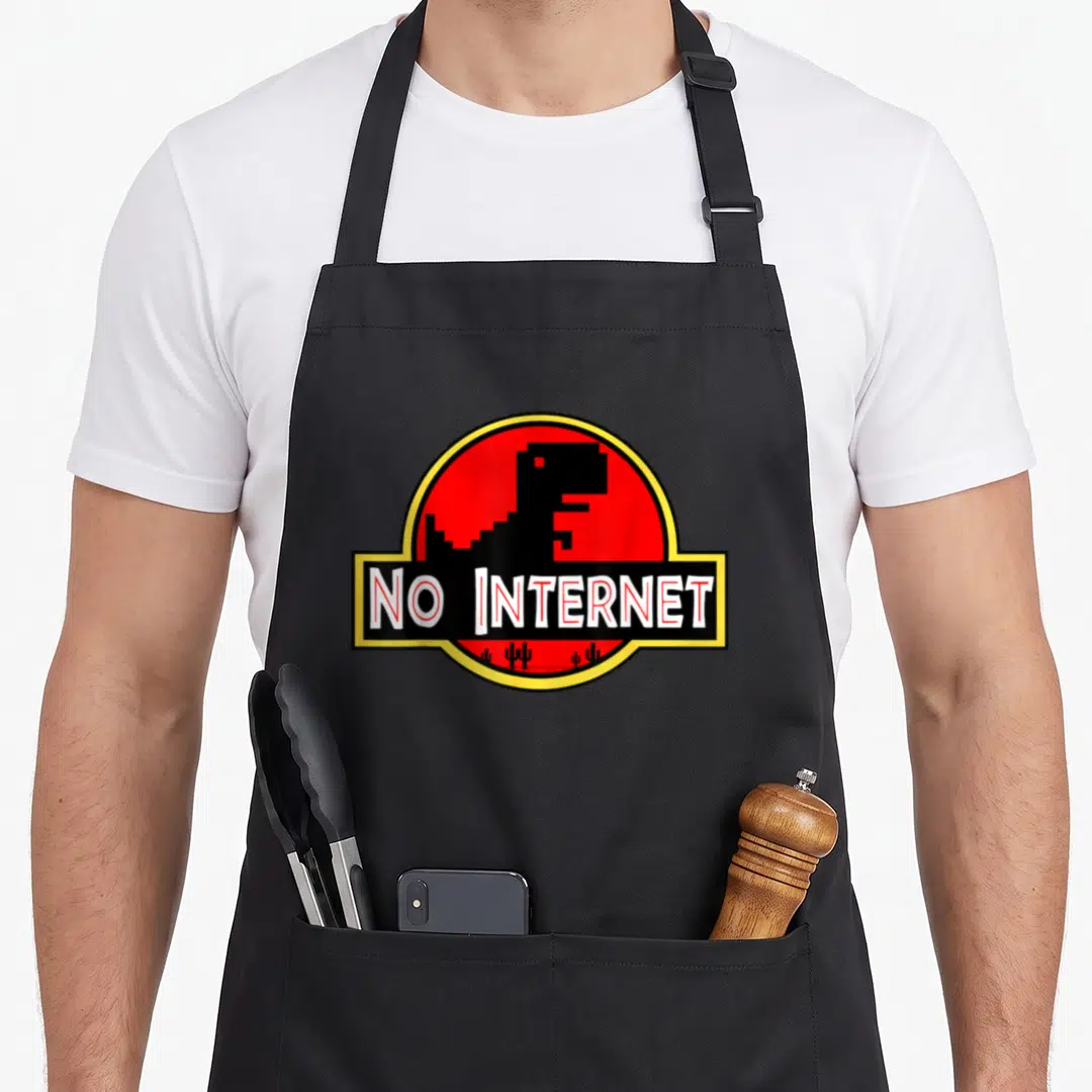 Internet teacher apron - Pixel dinosaur inside red circle with NO INTERNET text and cacti — shown on a black cotton canvas apron against a white background