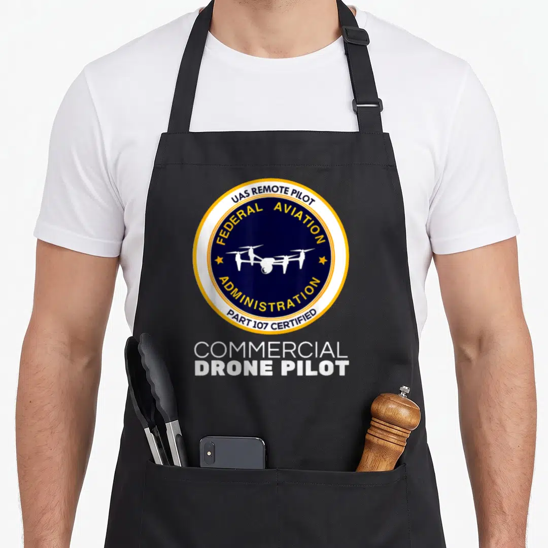 Faa commercial apron - Circular seal with drone and UAS REMOTE PILOT text above white COMMERCIAL DRONE PILOT lettering — shown on a black cotton canvas apron against a white background