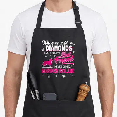 Vintage border collie apron - Pink border collie silhouette surrounded by white diamonds and stacked typography quote — shown on a black cotton canvas apron against a white background