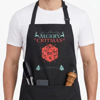 Critmas merry christmas apron - Red 20-sided die with MERRY CRITMAS text, light blue reindeer and trees, distressed — shown on a black cotton canvas apron against a white background