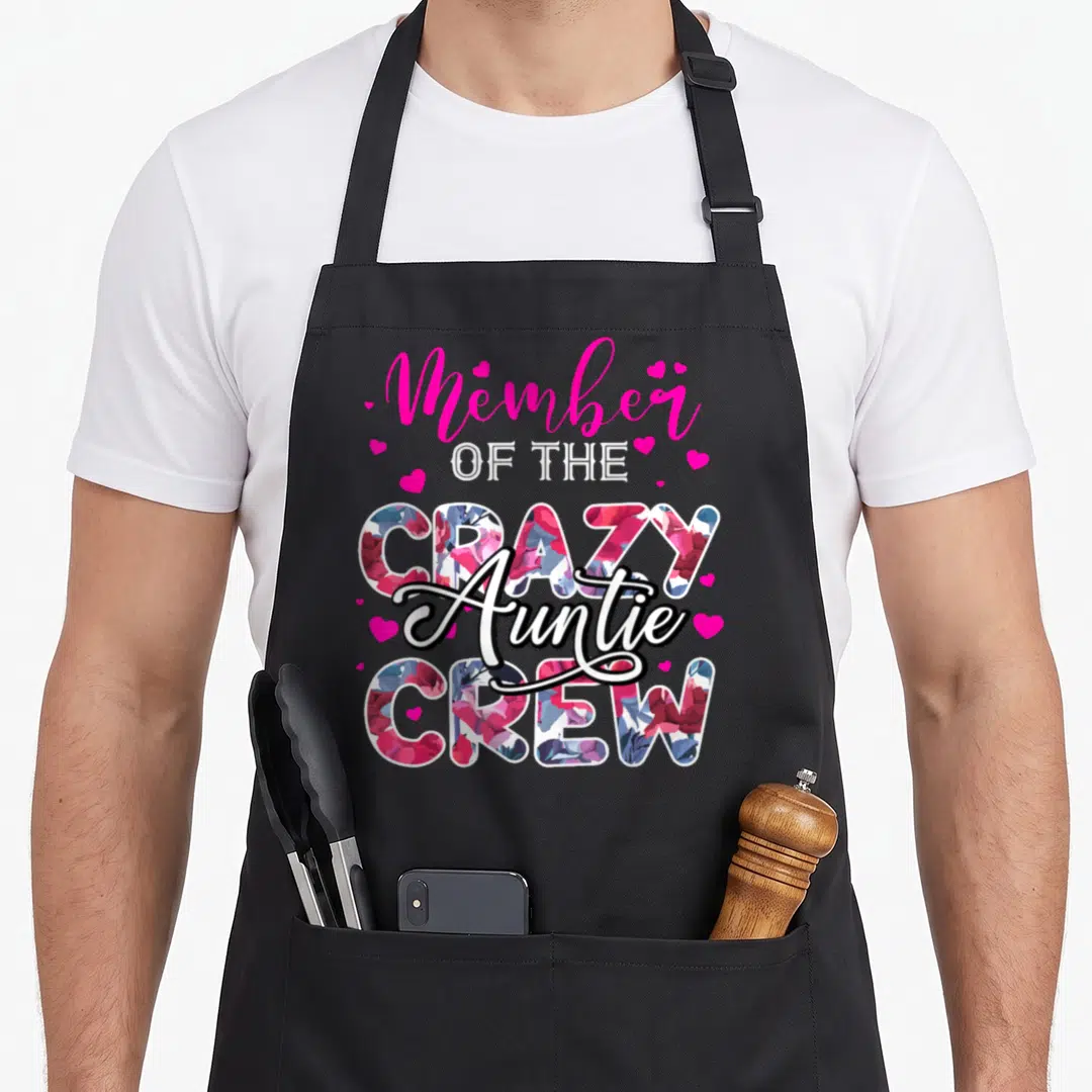 Flower family aprons - Vertical text Member OF THE CRAZY Auntie CREW with floral filled letters and pink hearts — shown on a black cotton canvas apron against a white background