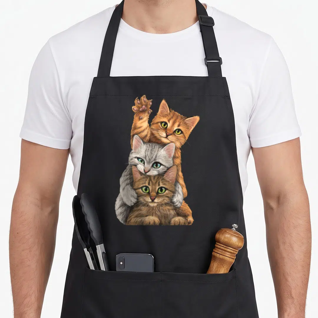 Build kitty cat apron - Three realistic kittens stacked vertically in orange grey and brown fur — shown on a black cotton canvas apron against a white background