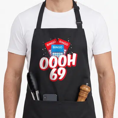 Player bingo aprons - Three red and blue bingo cards fanned behind white OOOH 69 text with small stars — shown on a black cotton canvas apron against a white background