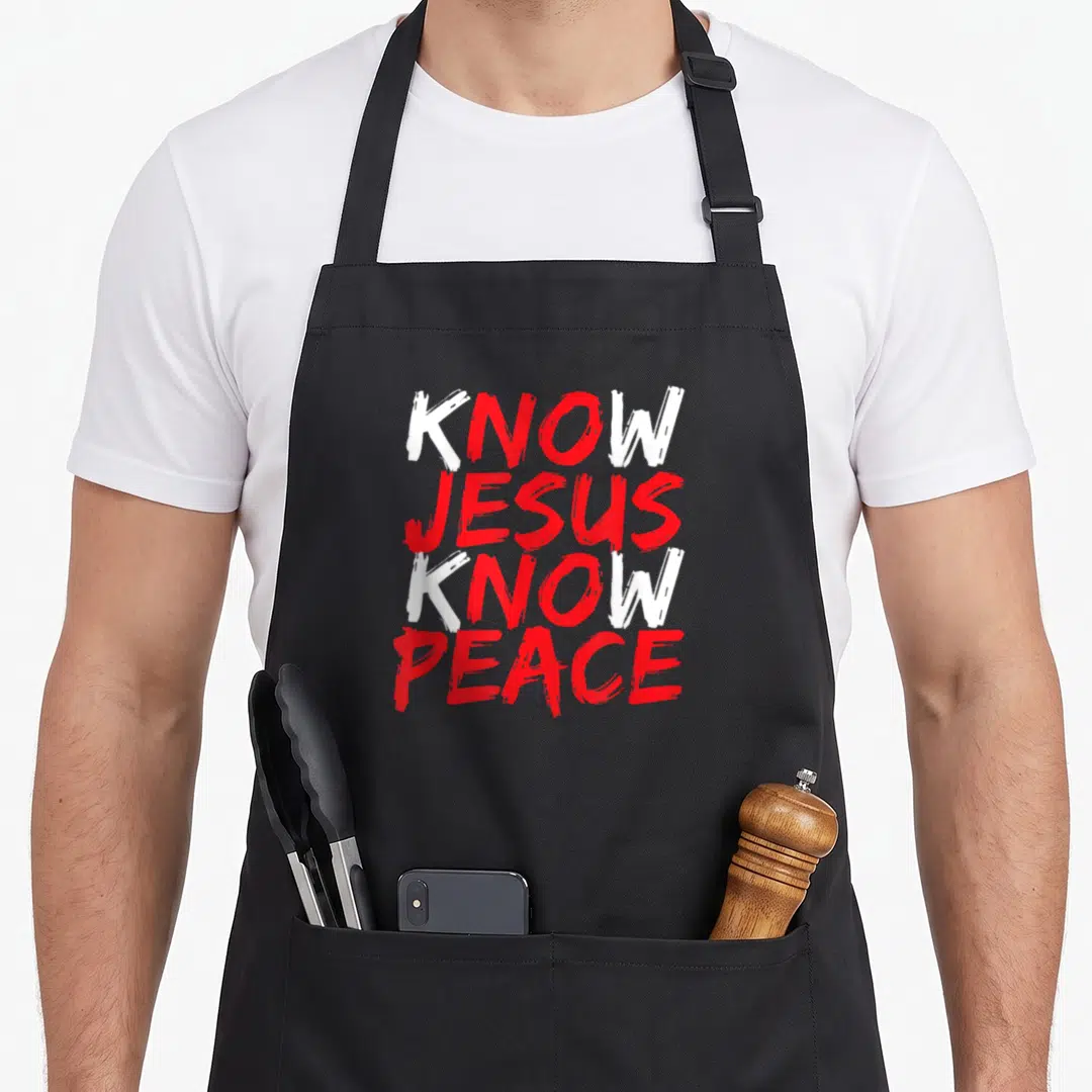Jesus bible verse apron - Stacked KNOW JESUS KNOW PEACE text in white and red brush stroke font — shown on a black cotton canvas apron against a white background