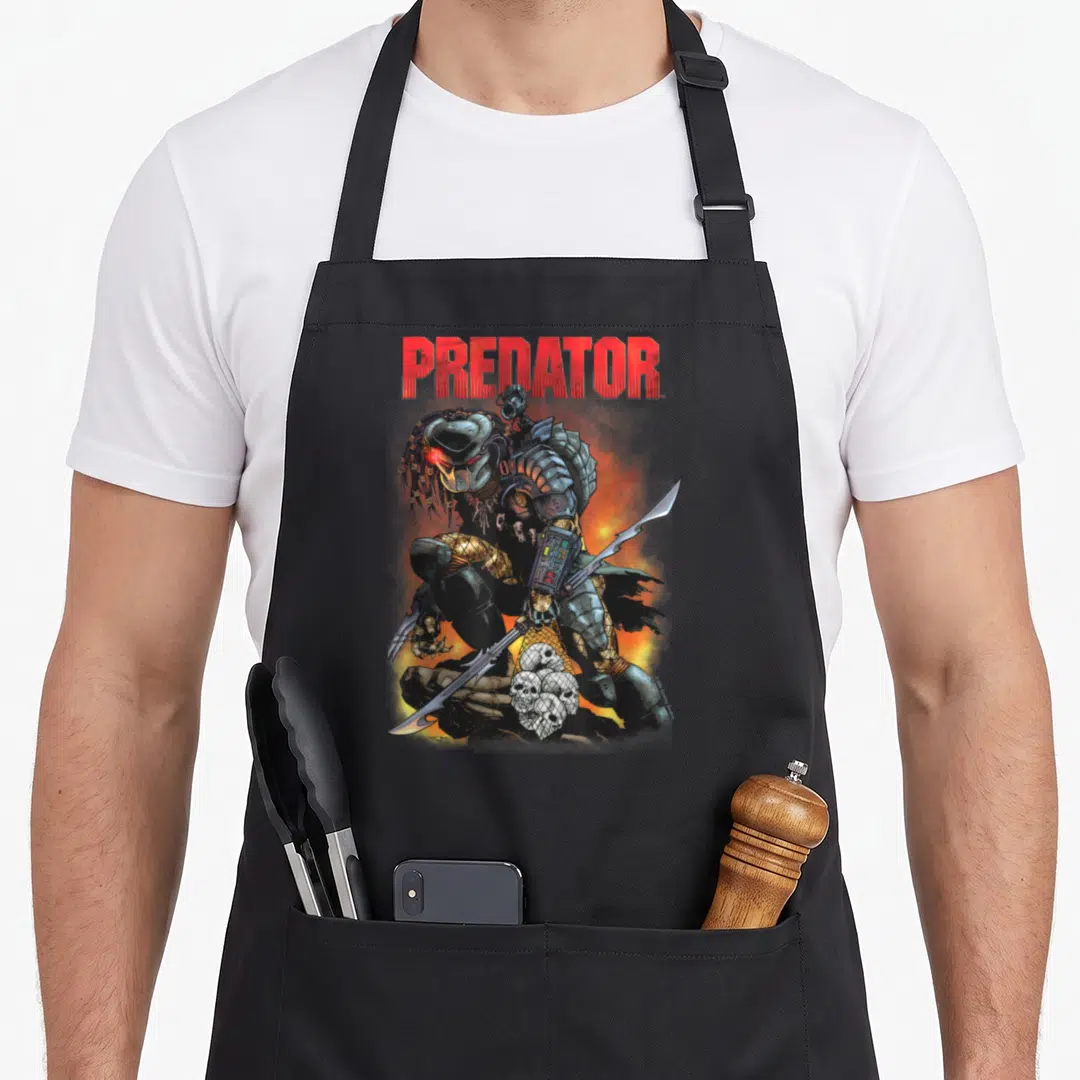 Ready predator apron - Crouching alien hunter holding spear and skull net under red PREDATOR text — shown on a black cotton canvas apron against a white background