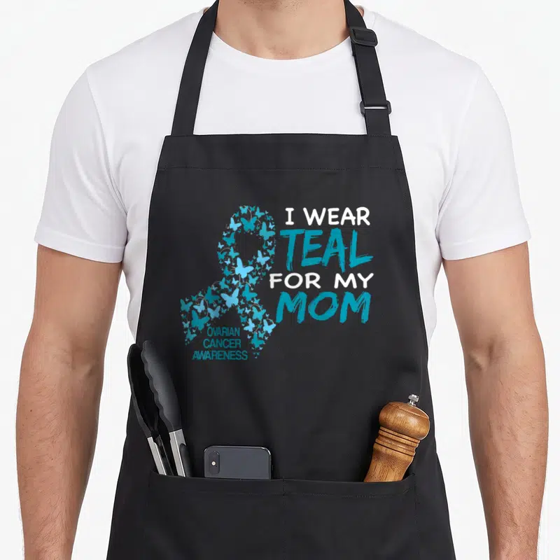 Ovarian crab dad apron - Teal butterfly awareness ribbon next to I WEAR TEAL FOR MY MOM text — shown on a black cotton canvas apron against a white background