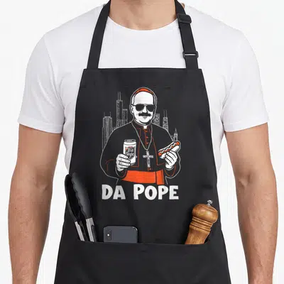 Pope chicago apron - Cartoon pope holding beer and hot dog with DA POPE text — shown on a black cotton canvas apron against a white background