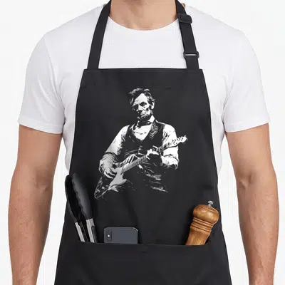 President playing guitar apron - White line-art sketch of Abraham Lincoln playing an electric guitar on dark fabric — shown on a black cotton canvas apron against a white background