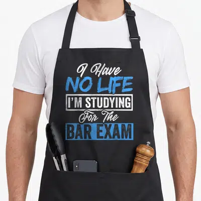 Studying study life apron - I Have No Life I'm Studying For The Bar Exam text in distressed blue and white typography — shown on a black cotton canvas apron against a white background