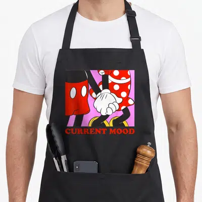 Current friends apron - Mickey and Minnie holding hands with CURRENT MOOD text in red on pink — shown on a black cotton canvas apron against a white background