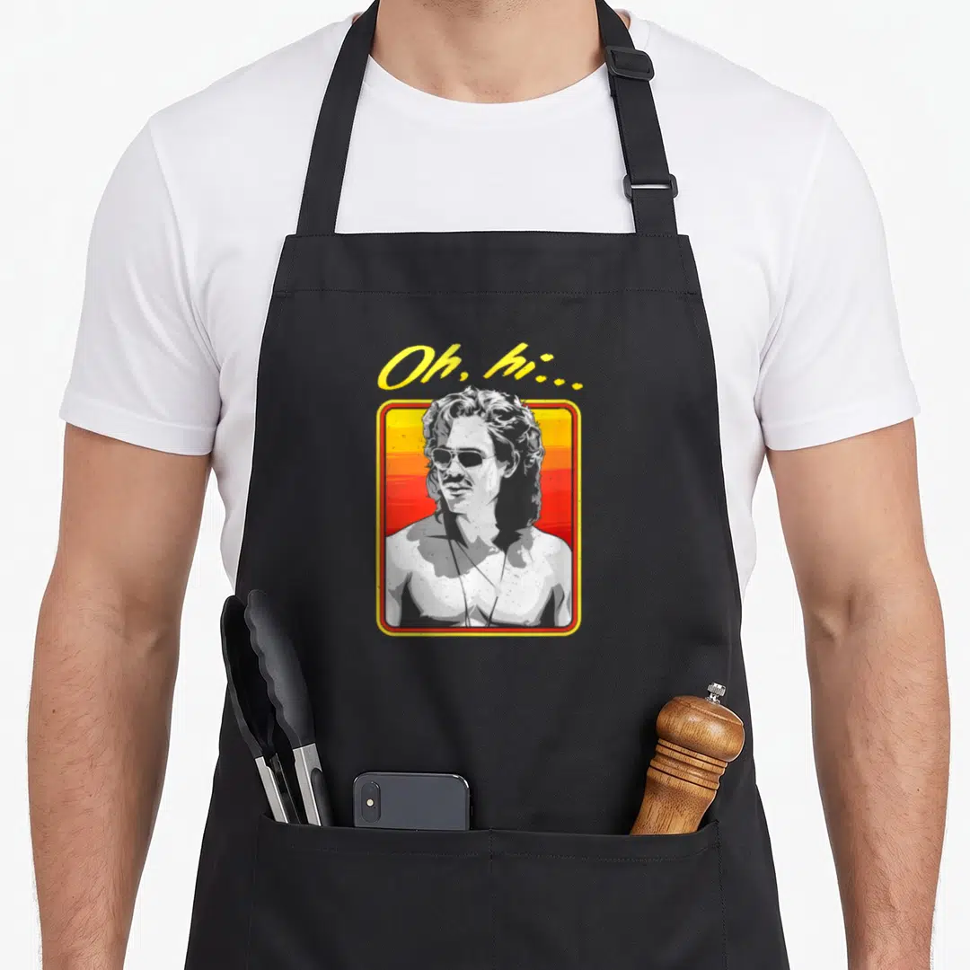 Greyscale billy apron - Oh hi text above man portrait in yellow frame with red gradient background — shown on a black cotton canvas apron against a white background