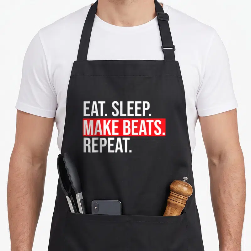 Eat beat apron - Stacked white text EAT SLEEP MAKE BEATS REPEAT with red block around middle line — shown on a black cotton canvas apron against a white background