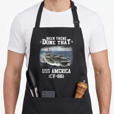 Uss veteran father day apron - USS America CV-66 aircraft carrier sailing with Been There Done That text and stars — shown on a black cotton canvas apron against a white background