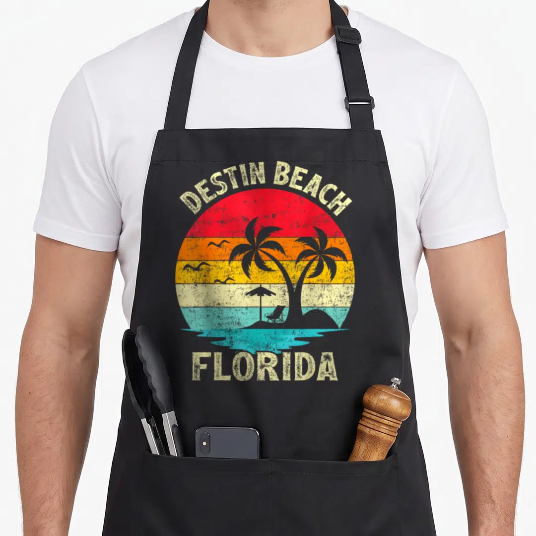 Vacation florida family aprons - Retro Destin Beach Florida sunset with palm trees, beach chair, and multi-colored bands — shown on a black cotton canvas apron against a white background