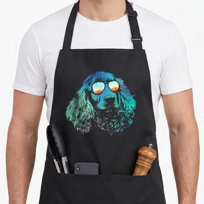 Disco cocker spaniel apron - Realistic dog head wearing sunglasses with blue teal and orange gradient fur — shown on a black cotton canvas apron against a white background