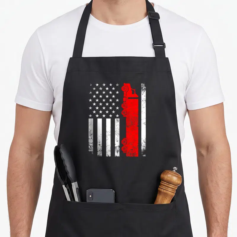 Driver wheeler american flag apron - Distressed USA flag with red fire truck silhouette replacing one stripe, white — shown on a black cotton canvas apron against a white background