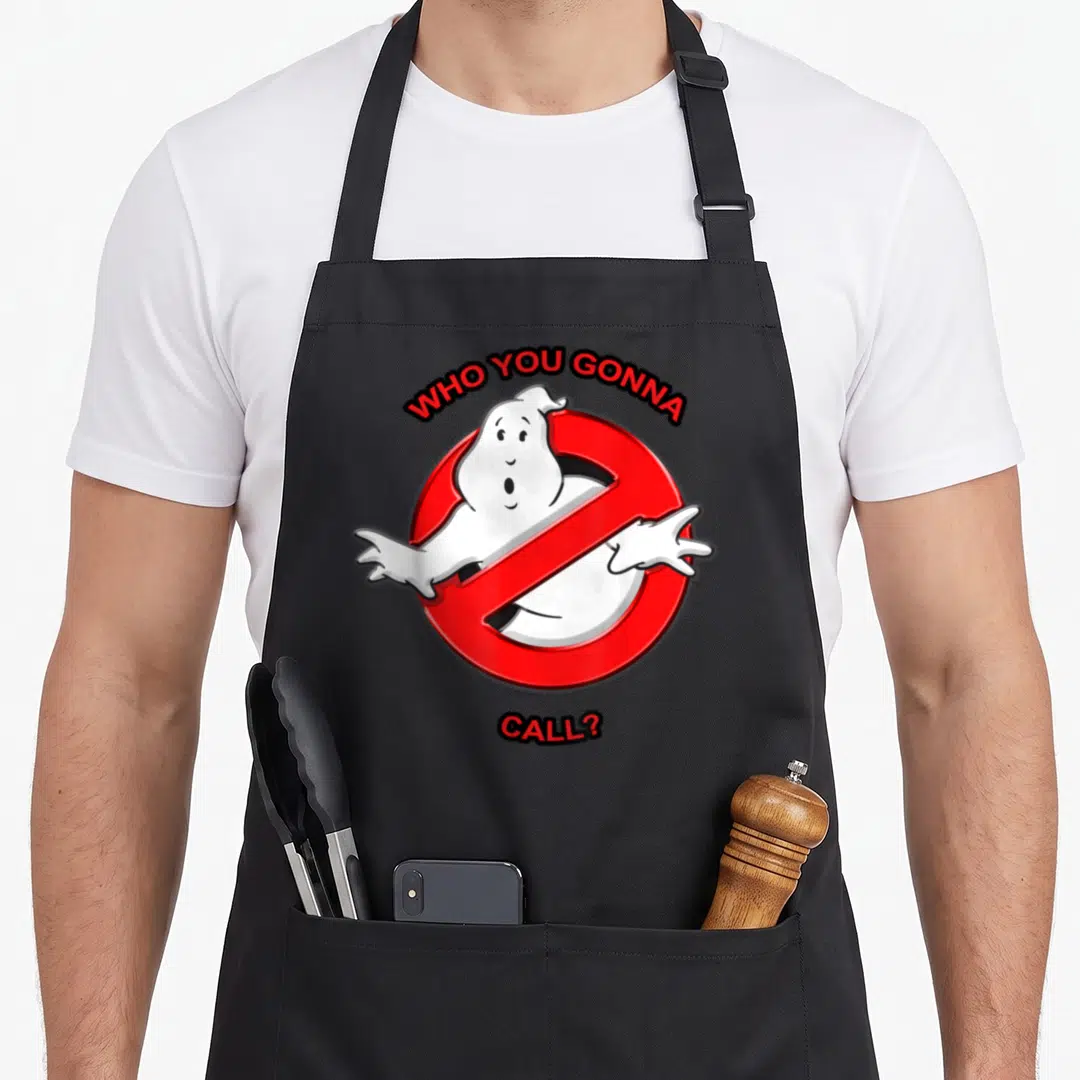 Call novelty apron - Red prohibition sign with white cartoon ghost and arched WHO YOU GONNA CALL text — shown on a black cotton canvas apron against a white background