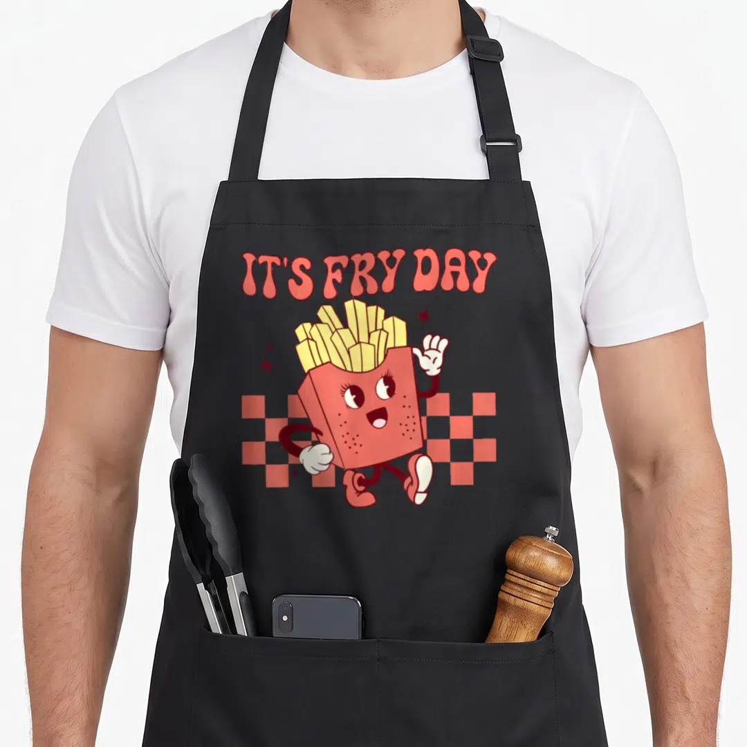 Fry fast french apron - Cartoon red fry container with face waving under arched IT'S FRY DAY text over checkerboard — shown on a black cotton canvas apron against a white background