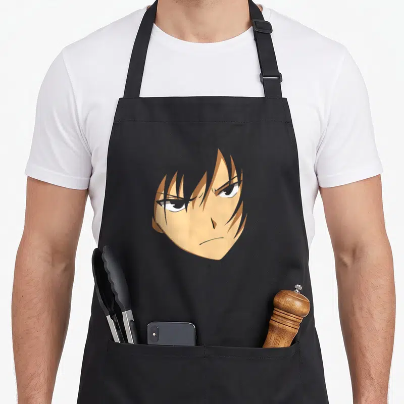 Face anime apron - Centered anime head with tan hair and brown outlines in cartoon style — shown on a black cotton canvas apron against a white background
