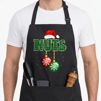 Nut chestnut family christmas aprons - NUTS text in green plaid with Santa hat and two snowflake baubles hanging below — shown on a black cotton canvas apron against a white background
