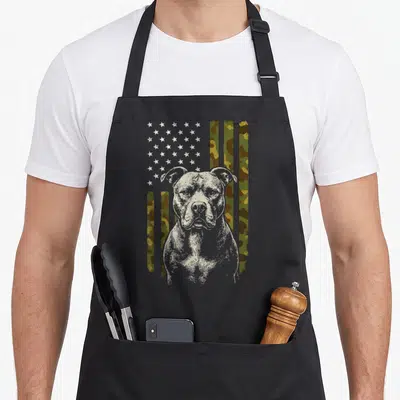 Pitbull us aprons - Distressed dog portrait over vertical camo flag stripes in green and brown — shown on a black cotton canvas apron against a white background