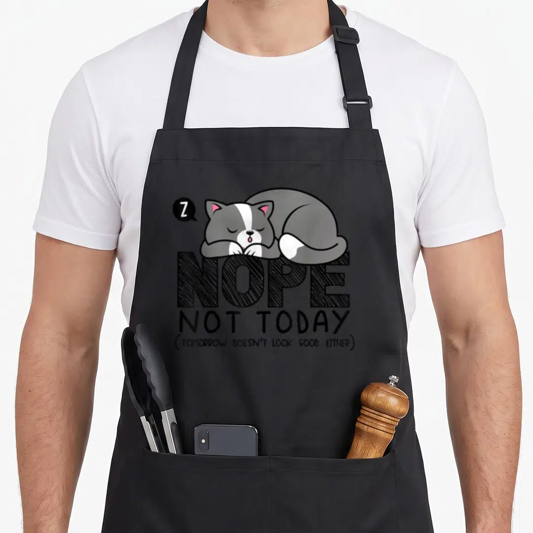 Procrastinator cat apron - Sleeping grey cat on NOPE text with Z bubble and sarcastic quote — shown on a black cotton canvas apron against a white background