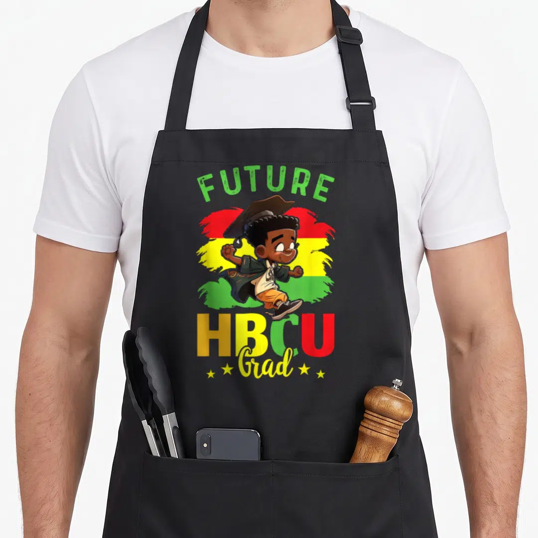 College future history apron - Cartoon boy in cap and gown over red yellow green splash with FUTURE HBCU Grad text — shown on a black cotton canvas apron against a white background