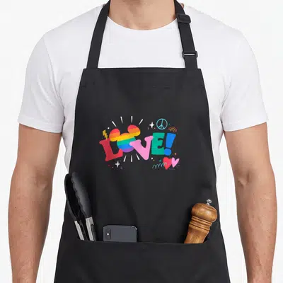 Doodle rainbow apron - LOVE! text with striped mouse head, peace sign, rainbow, stars in red pink blue yellow purple — shown on a black cotton canvas apron against a white background