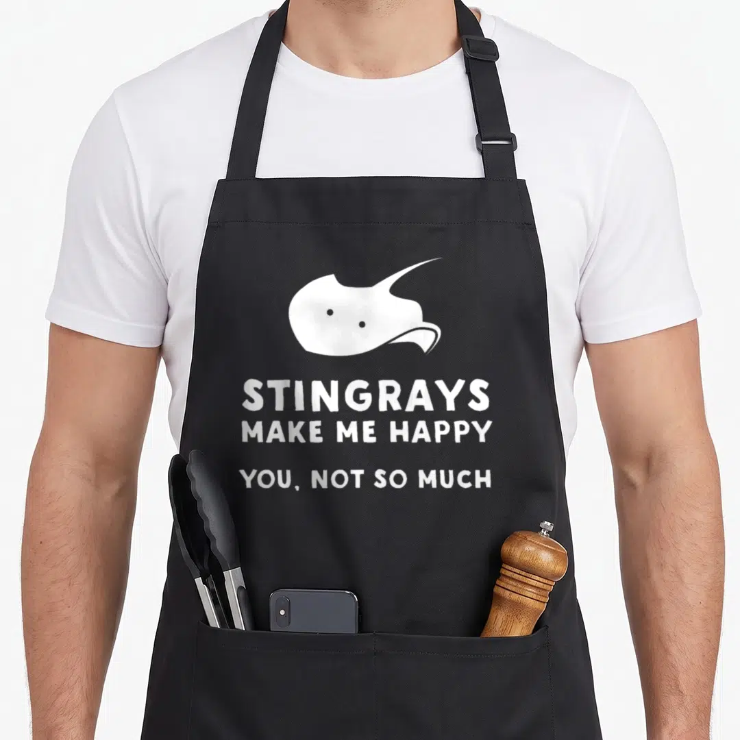 Funny stingray apron - White stingray silhouette above text reading STINGRAYS MAKE ME HAPPY YOU NOT SO MUCH — shown on a black cotton canvas apron against a white background