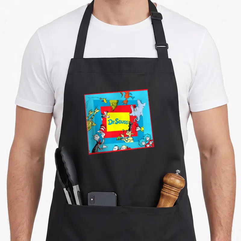 Cute character aprons - Dr. Seuss text in yellow box surrounded by cartoon characters on blue with red border — shown on a black cotton canvas apron against a white background