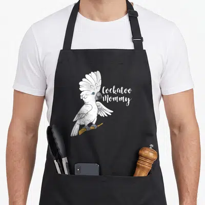 Cockatoo parrot bird apron - Realistic white cockatoo perched on branch next to Cockatoo Mommy script text — shown on a black cotton canvas apron against a white background