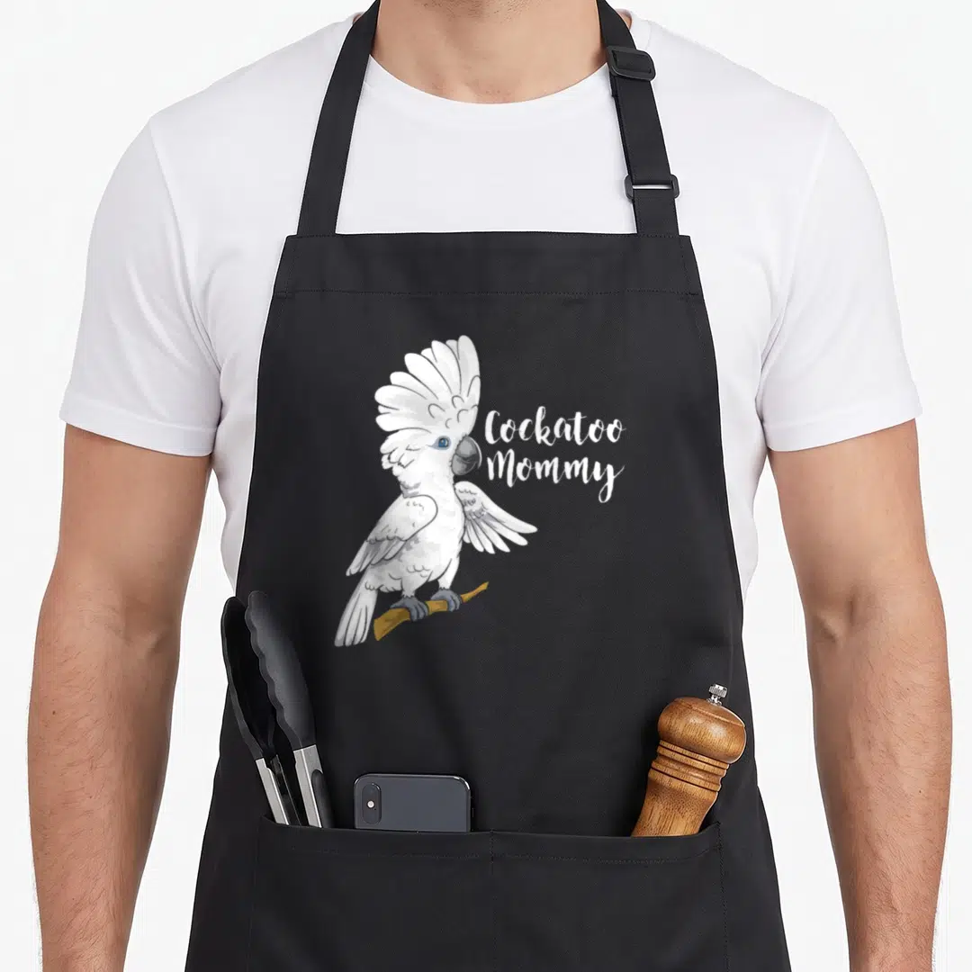Cockatoo parrot bird apron - Realistic white cockatoo perched on branch next to Cockatoo Mommy script text — shown on a black cotton canvas apron against a white background