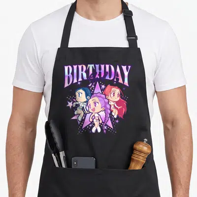 Chibi shot birthday apron - Three chibi anime girls below holographic BIRTHDAY Girl text over a large star in purple — shown on a black cotton canvas apron against a white background