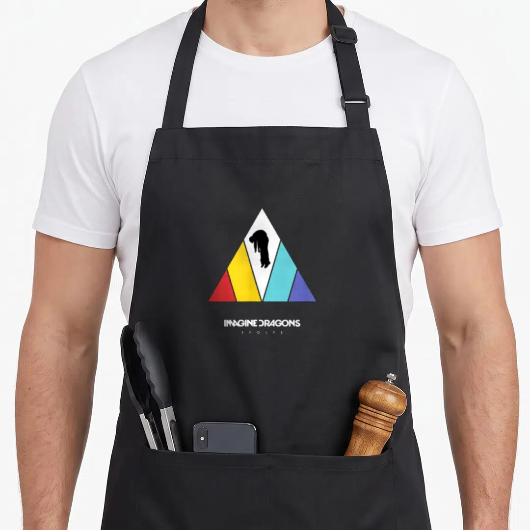 Imagine dragon apron - Multi-color triangle with black person silhouette, IMAGINE DRAGONS EVOLVE text below — shown on a black cotton canvas apron against a white background
